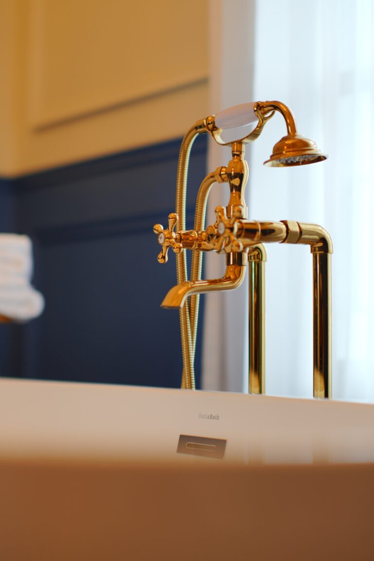 Large bathtub with gold colored faucet and shower head