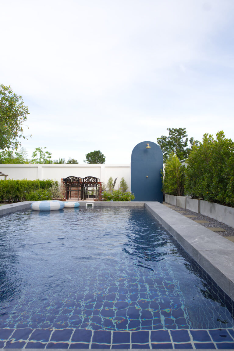 View of swimming pool with in background outdoor shower and barbecue area